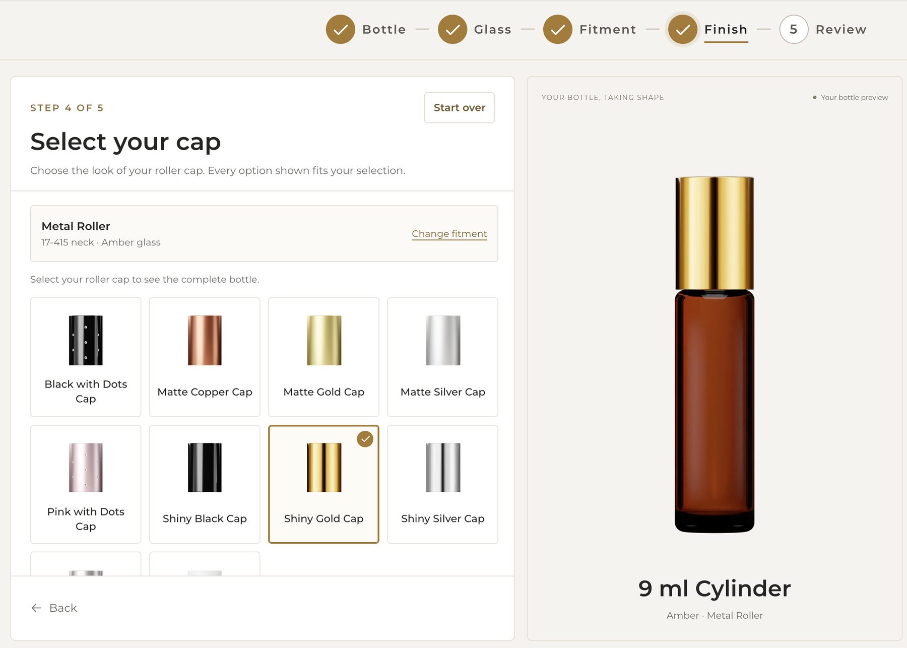 Build Your Bottle at the cap step: ten roller caps with Shiny Gold selected; the preview shows the amber bottle with a gold cap.